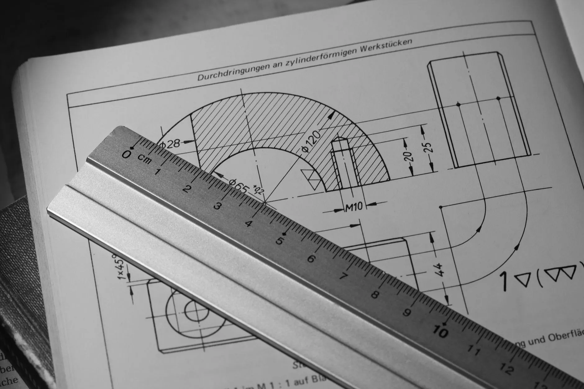 A technical drawing of a machined part with a steel rule laid across it