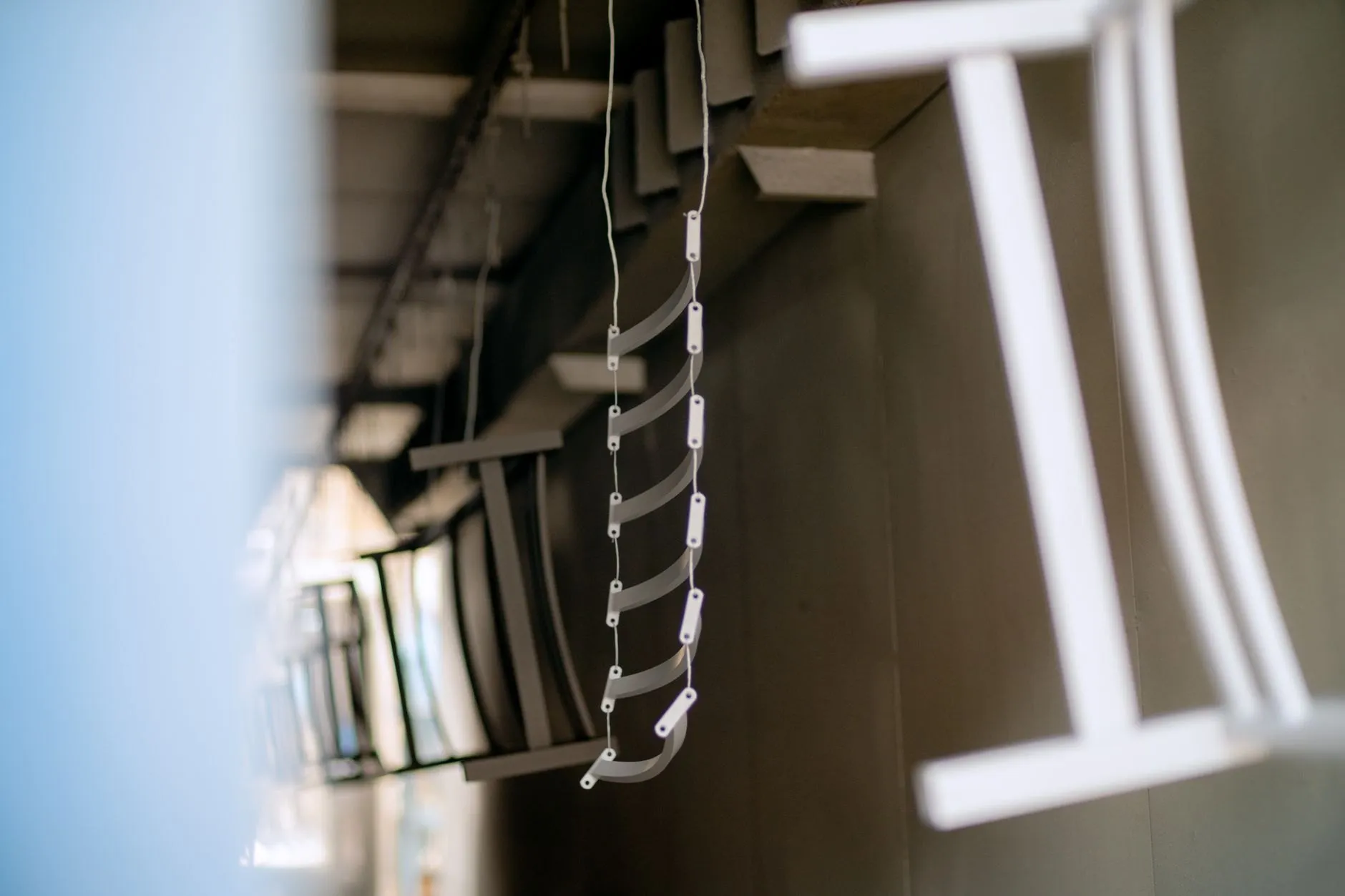 Freshly powder-coated white parts hanging from hooks on the coating line