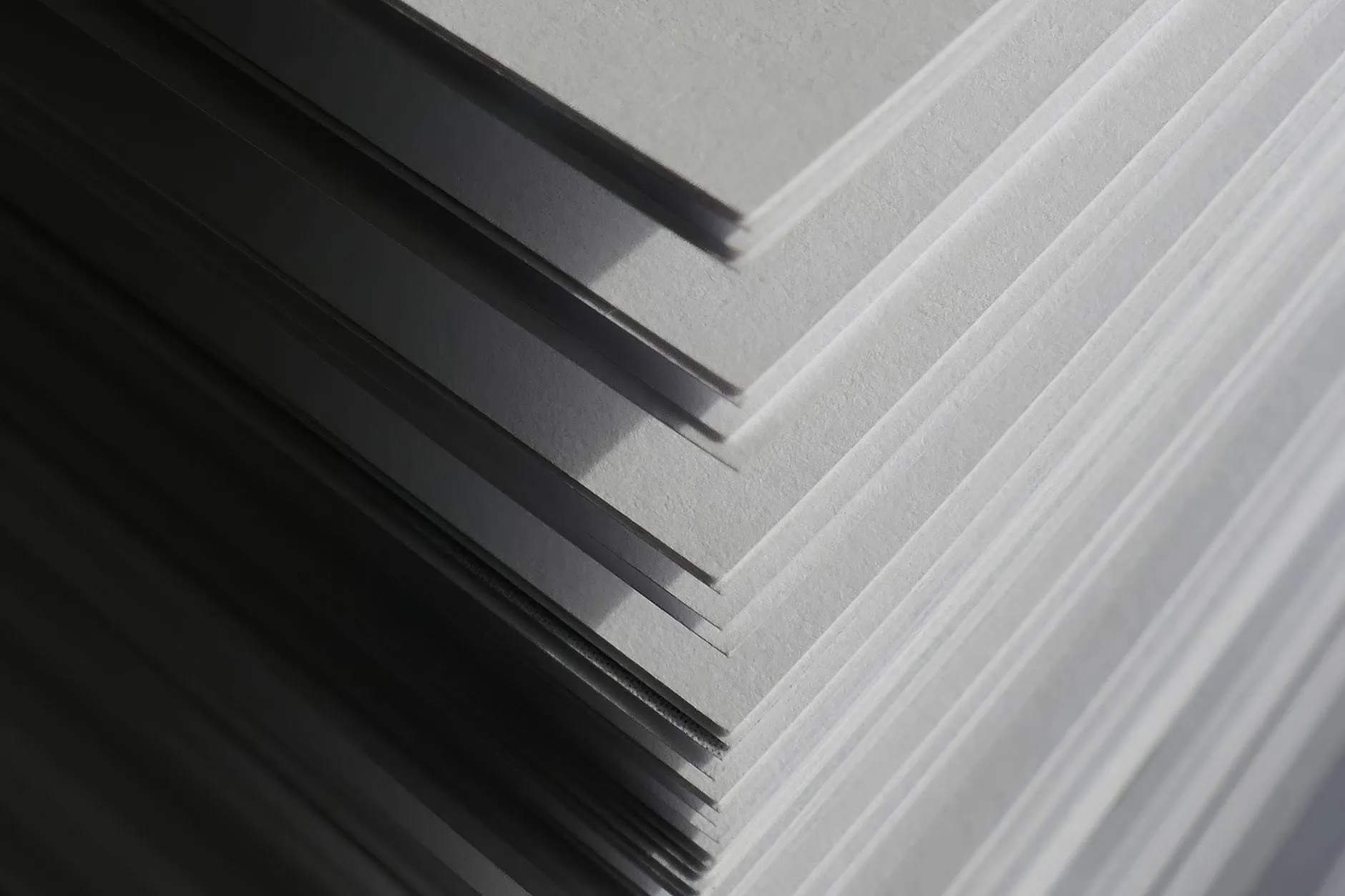 A stack of flat steel sheets fanned at the corner, waiting to be cut